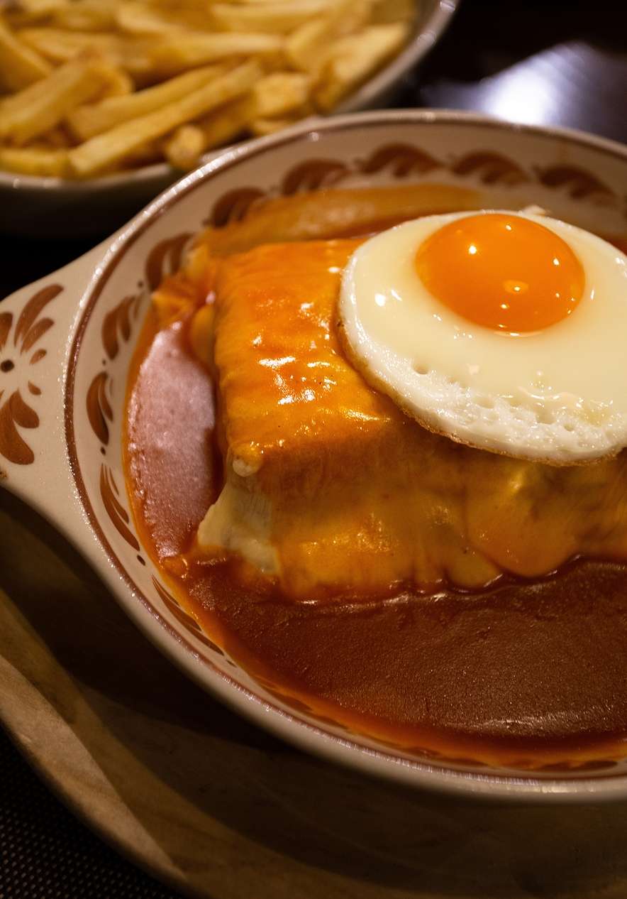 Francesinha tradicional, um dos pratos mais famosos do Porto, com queijo, ovo, molho picante e batata frita