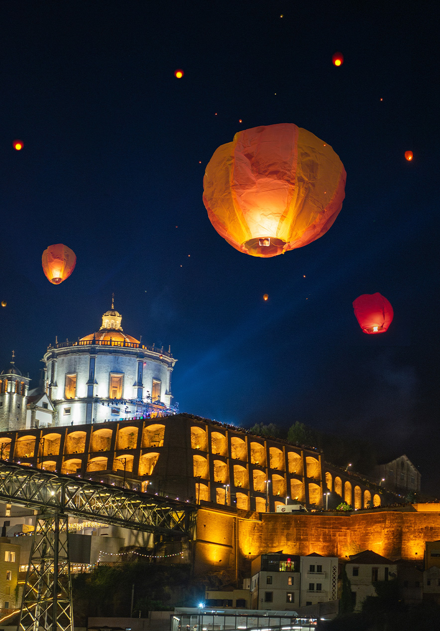 Festas de São João no Porto com balões de papel iluminados sobre edifícios históricos junto ao rio Douro