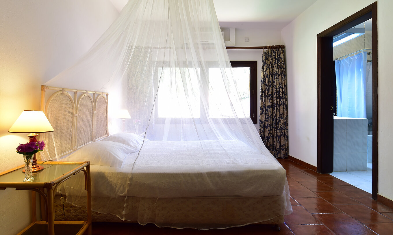 A Suite do Pestana Miramar São Tomé tem uma cama de casa com rede mosquiteira, uma mesa de cabeceira e uma janela