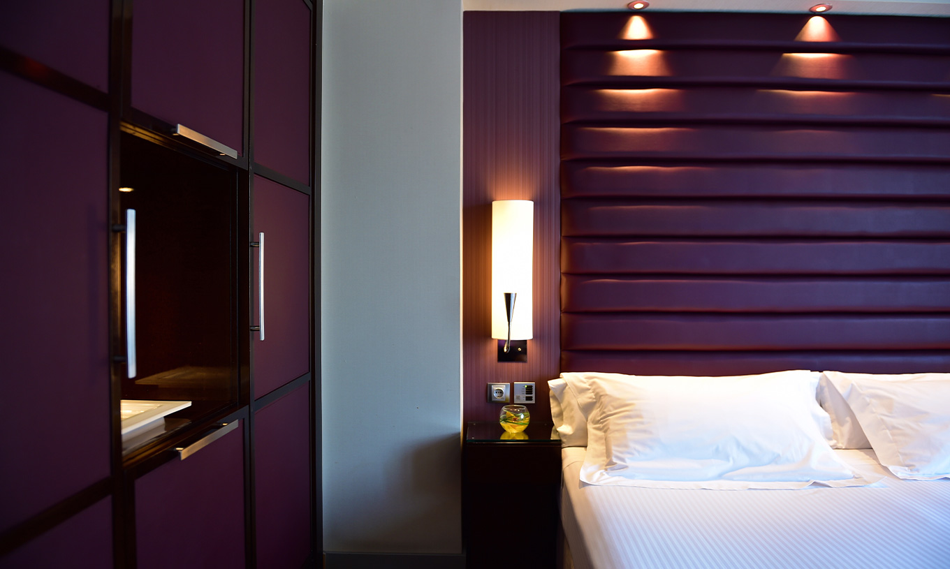 Quarto Familiar Grande no Pestana Arena Barcelona com cama branca, cabeceira roxa e roupeiro moderno
