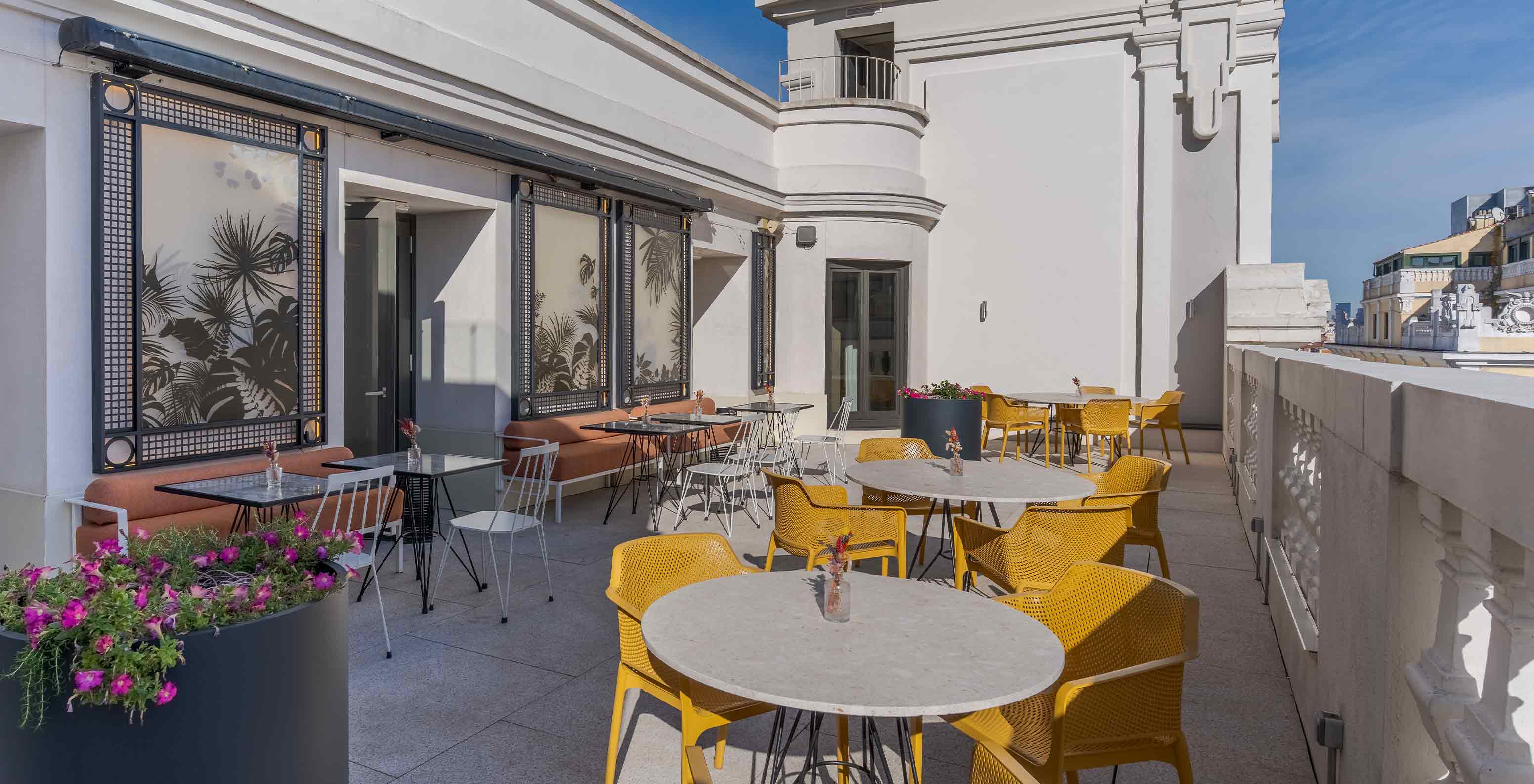 Varanda soalheira perto do Pestana CR7 Gran Vía Madrid, Hotel no Centro de Madrid, em Espanha com mesas ao ar livre