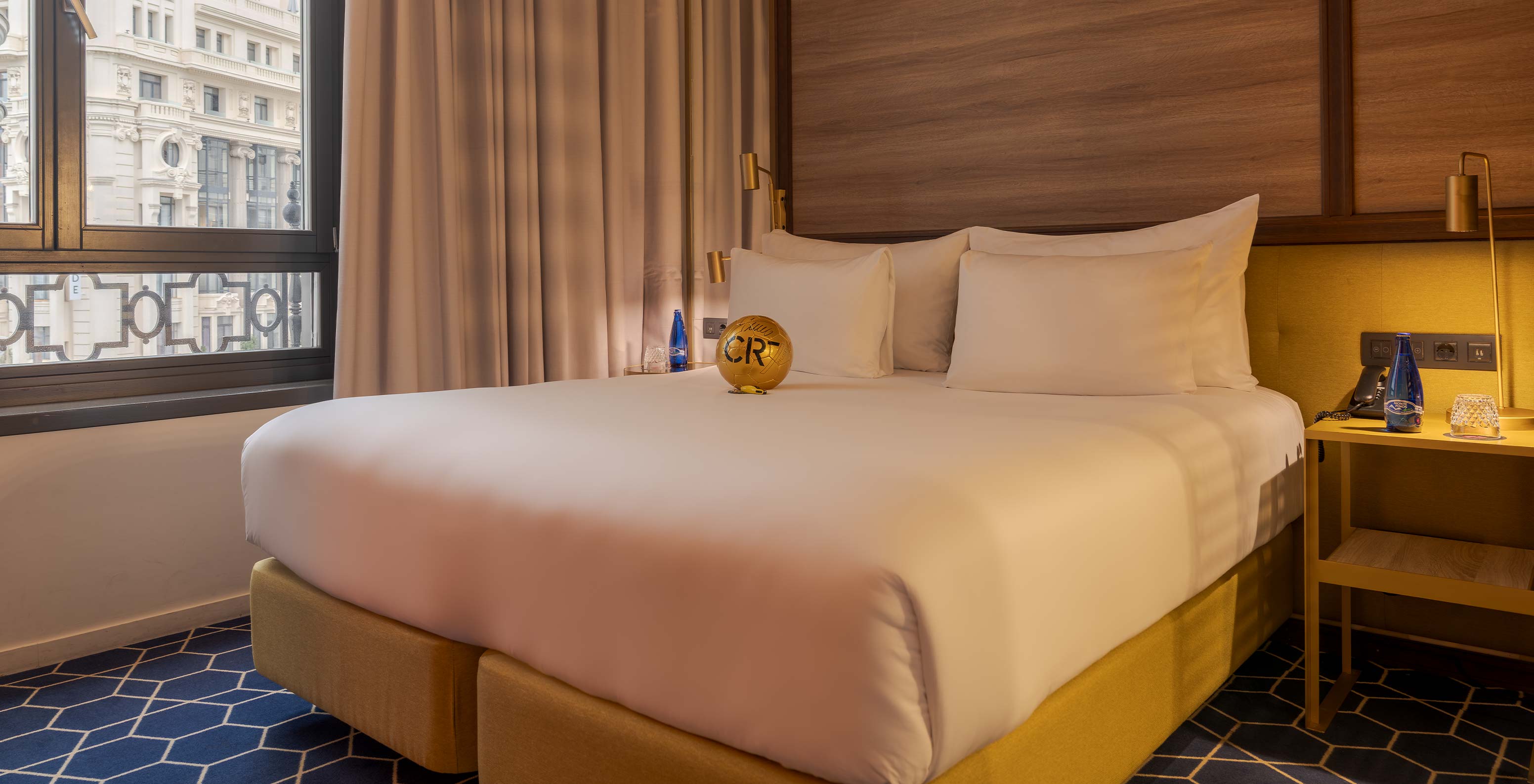 Quarto do Pestana CR7 Gran Vía Madrid com cama ampla, almofadas brancas e janela com vista urbana suave