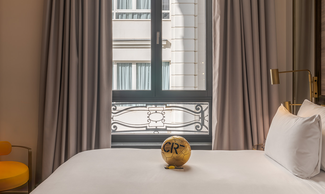 Quarto Premium no Pestana CR7 Gran Vía Madrid, com cama junto à janela e bola dourada sobre lençóis