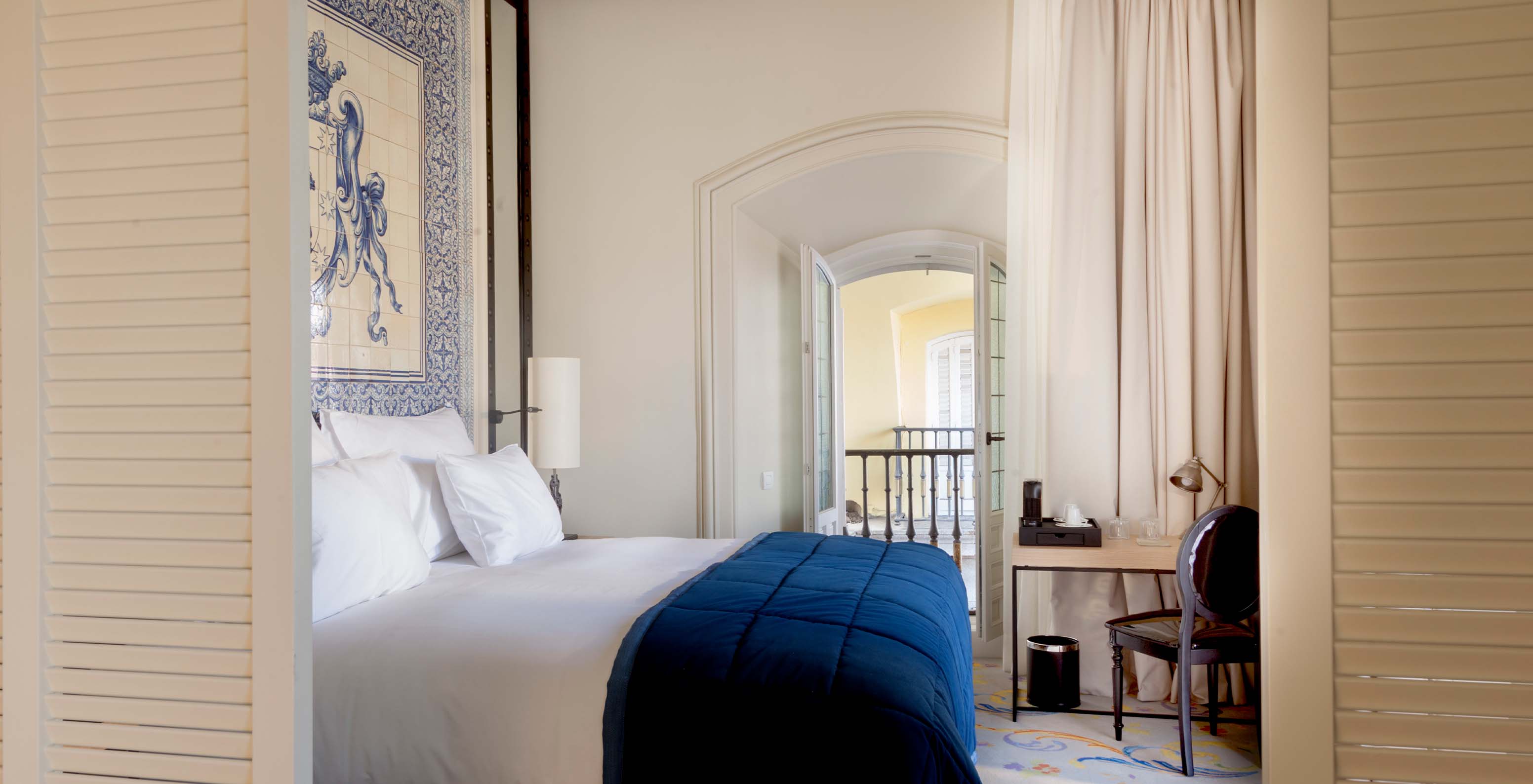 A Suite Plaza Mayor do Pestana Plaza Mayor Madrid tem uma cama de casal e uma cabeceira de cama com azulejos azuis e brancos