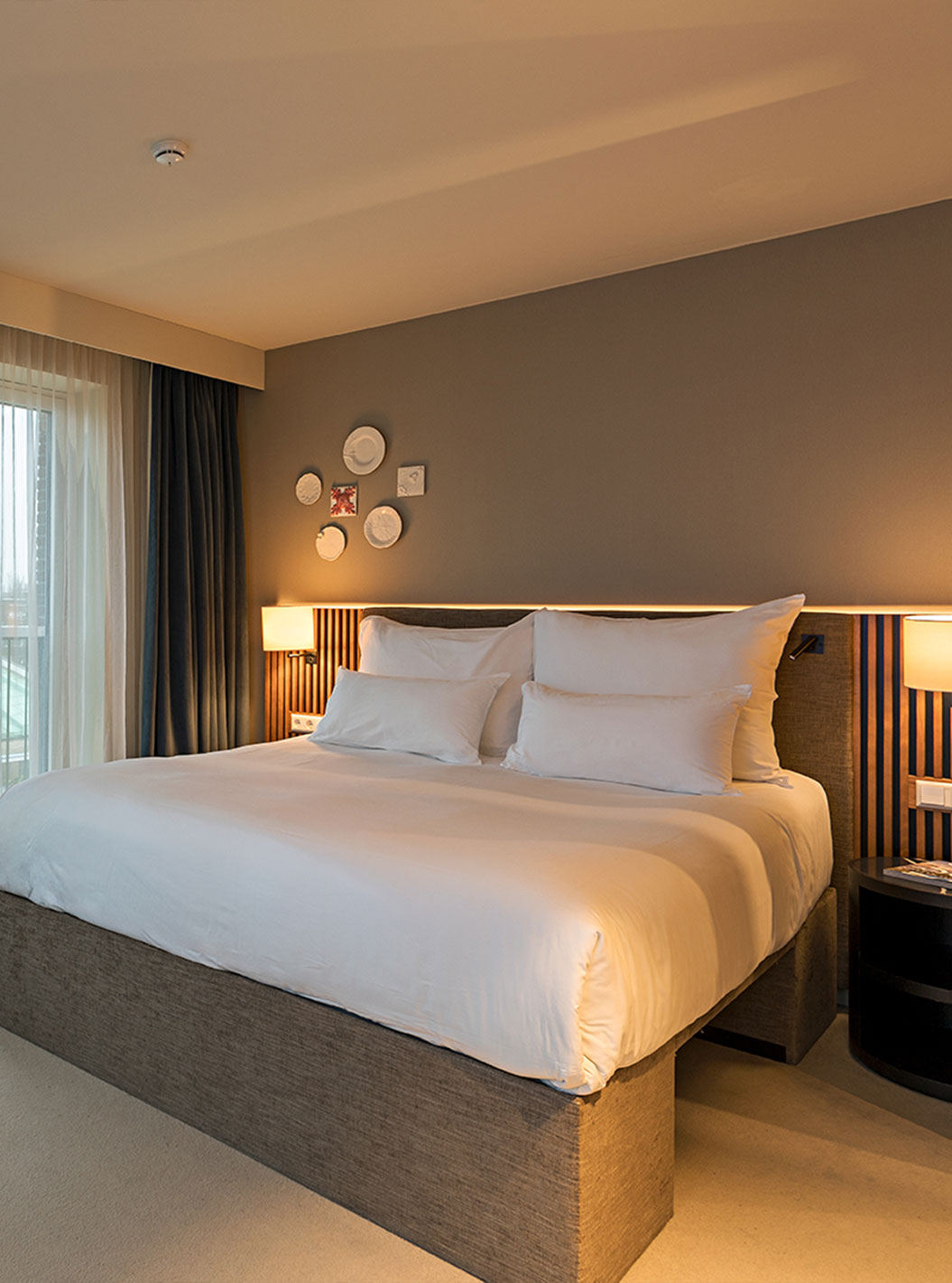 Classic Studio do Pestana Amsterdam Riverside com cama de casal, mesa com flores e janelas amplas com cortinas