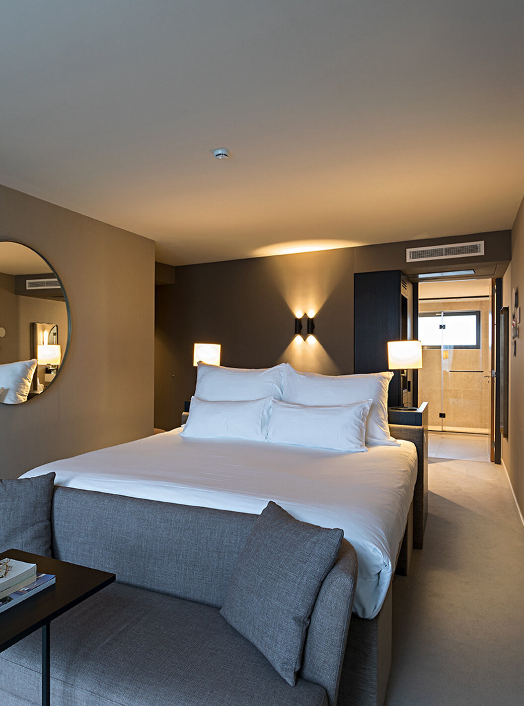 O quarto Executive - River View do Pestana Amsterdam Riverside tem uma cama de casal, com um sofá à frente da cama, e espelho