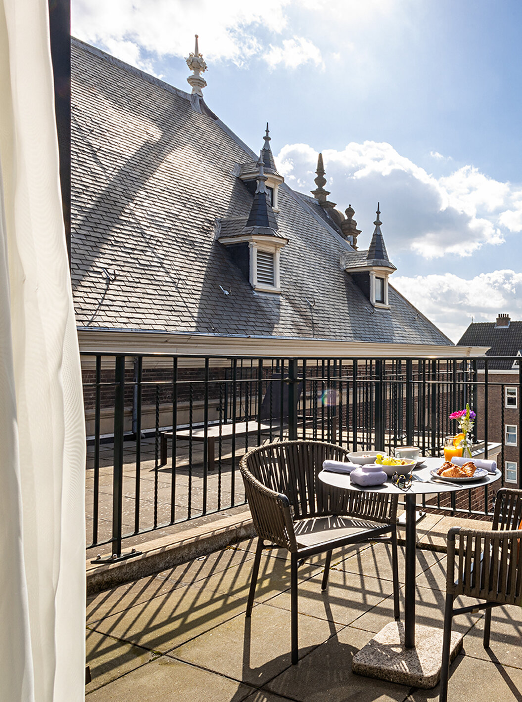 O quarto Executive Terrace do Pestana Amsterdam Riverside tem uma varanda, com uma mesa com comida, e duas cadeiras