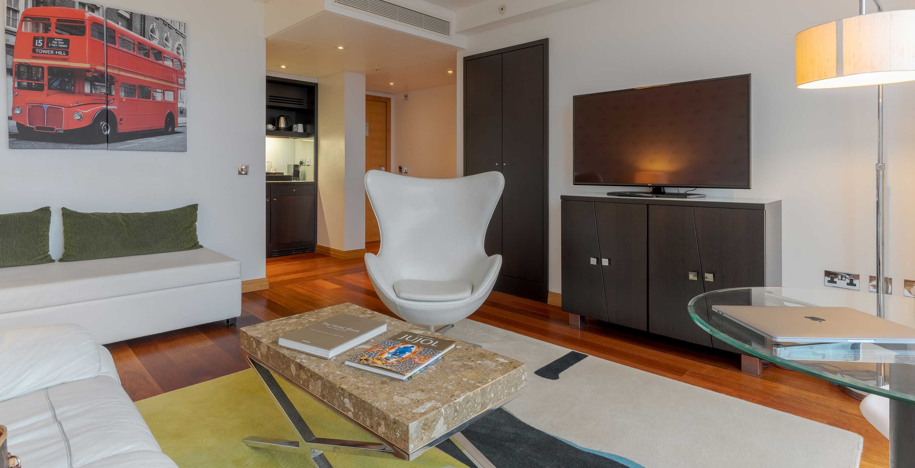 A Executive One Bedroom Suite do Pestana Chelsea Bridge tem sala de estar com sofá, mesa de centro, poltrona e televisão