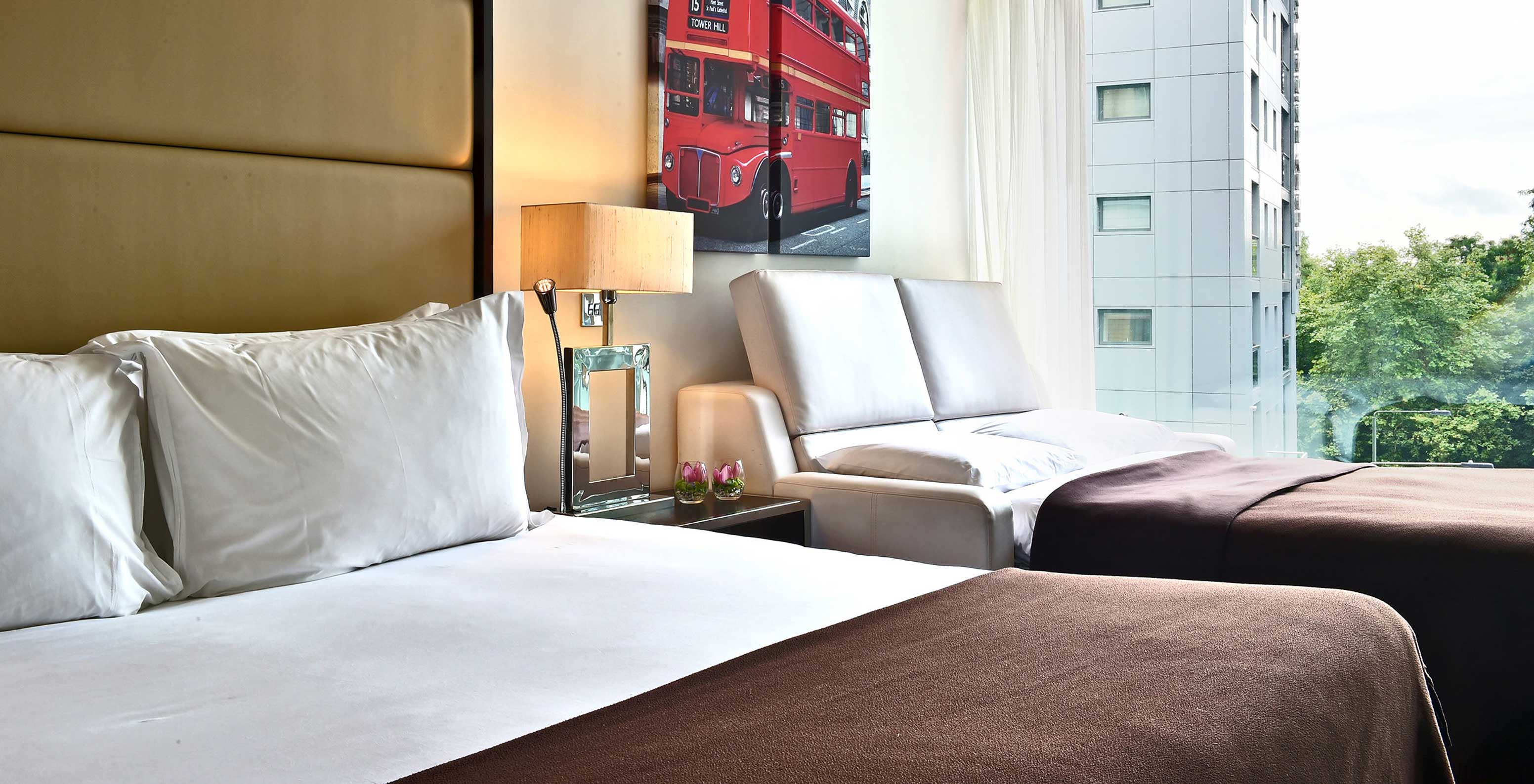 O Deluxe Family do Pestana Chelsea Bridge tem cama de casal, sofá cama aberto, quadros de londres e janela com vista