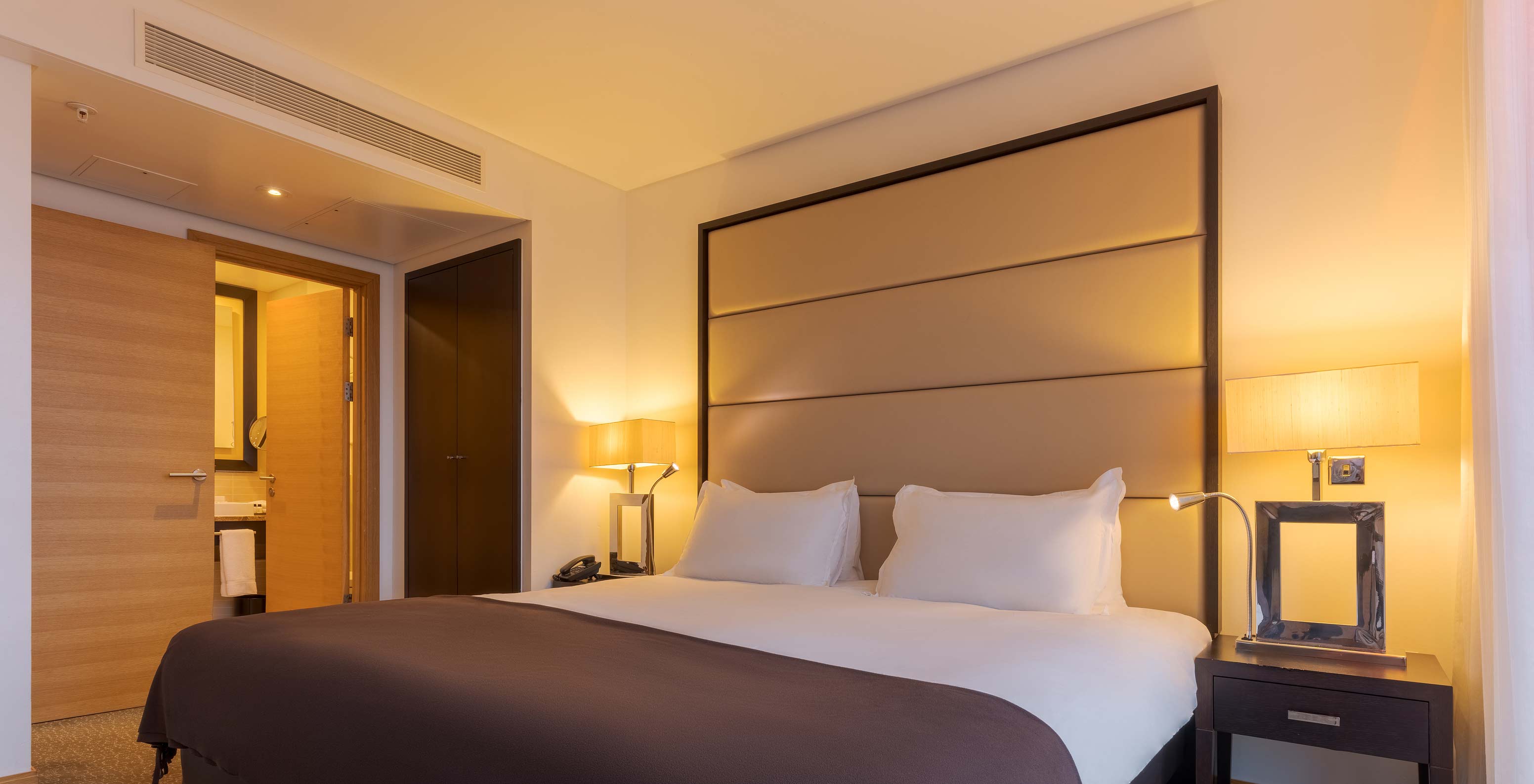 A Executive One Bedroom Suite do Pestana Chelsea Bridge tem cama de casal e duas mesas de cabeceira com candeeiro
