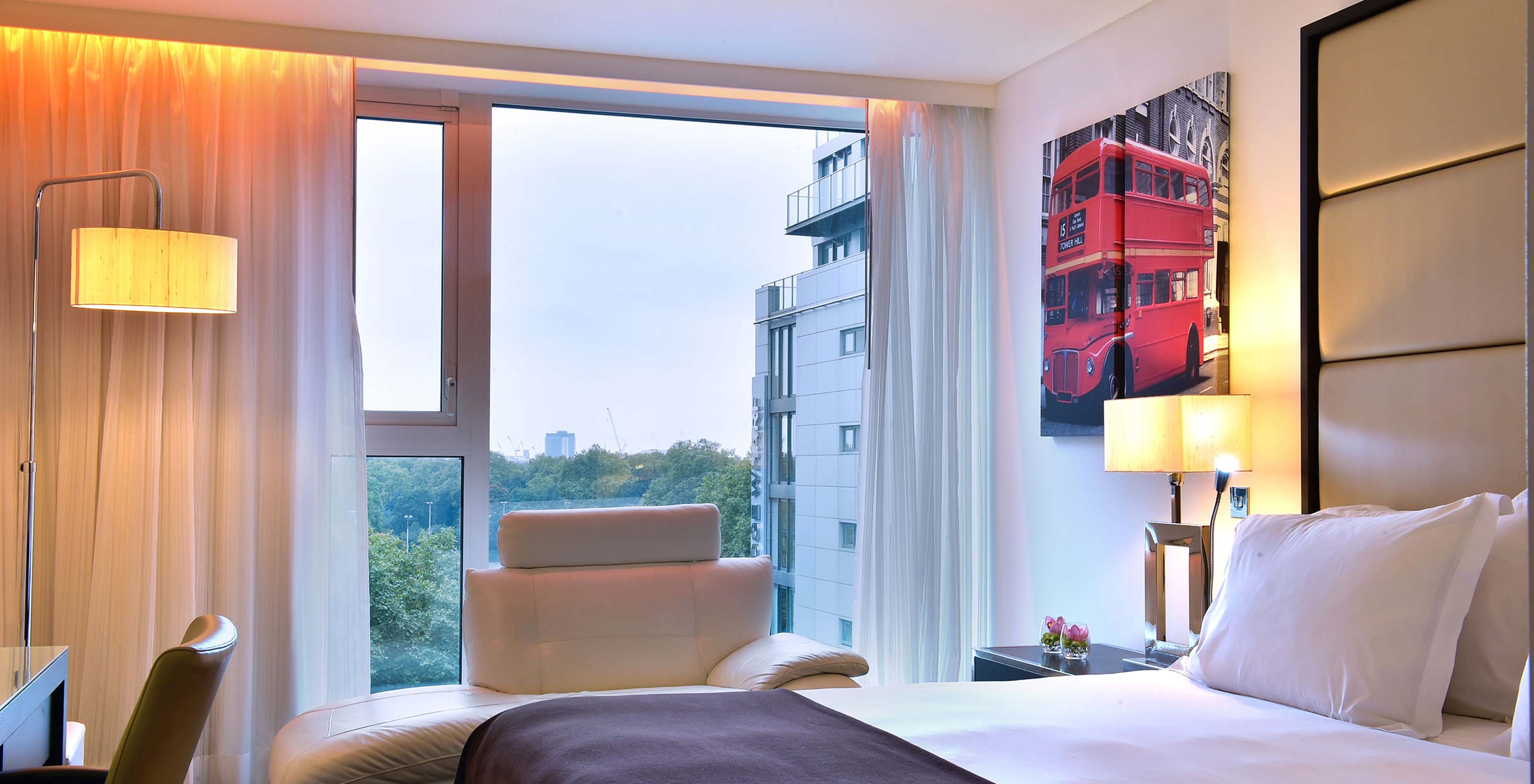 O Premium King do Pestana Chelsea Bridge tem cama de casal, secretária com cadeira, sofá, e janela grande com vista