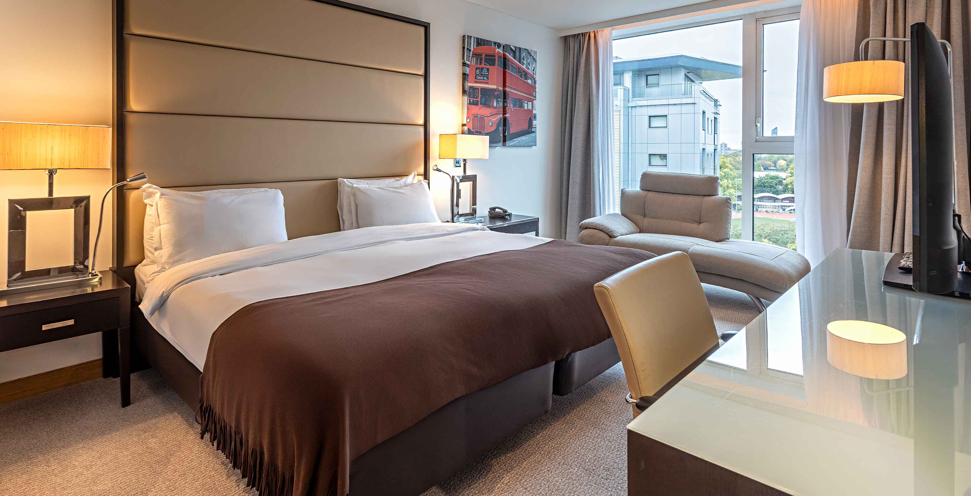 Quarto Premium King no Pestana Chelsea Bridge, com cama ampla, secretária, poltrona e janela com vista urbana