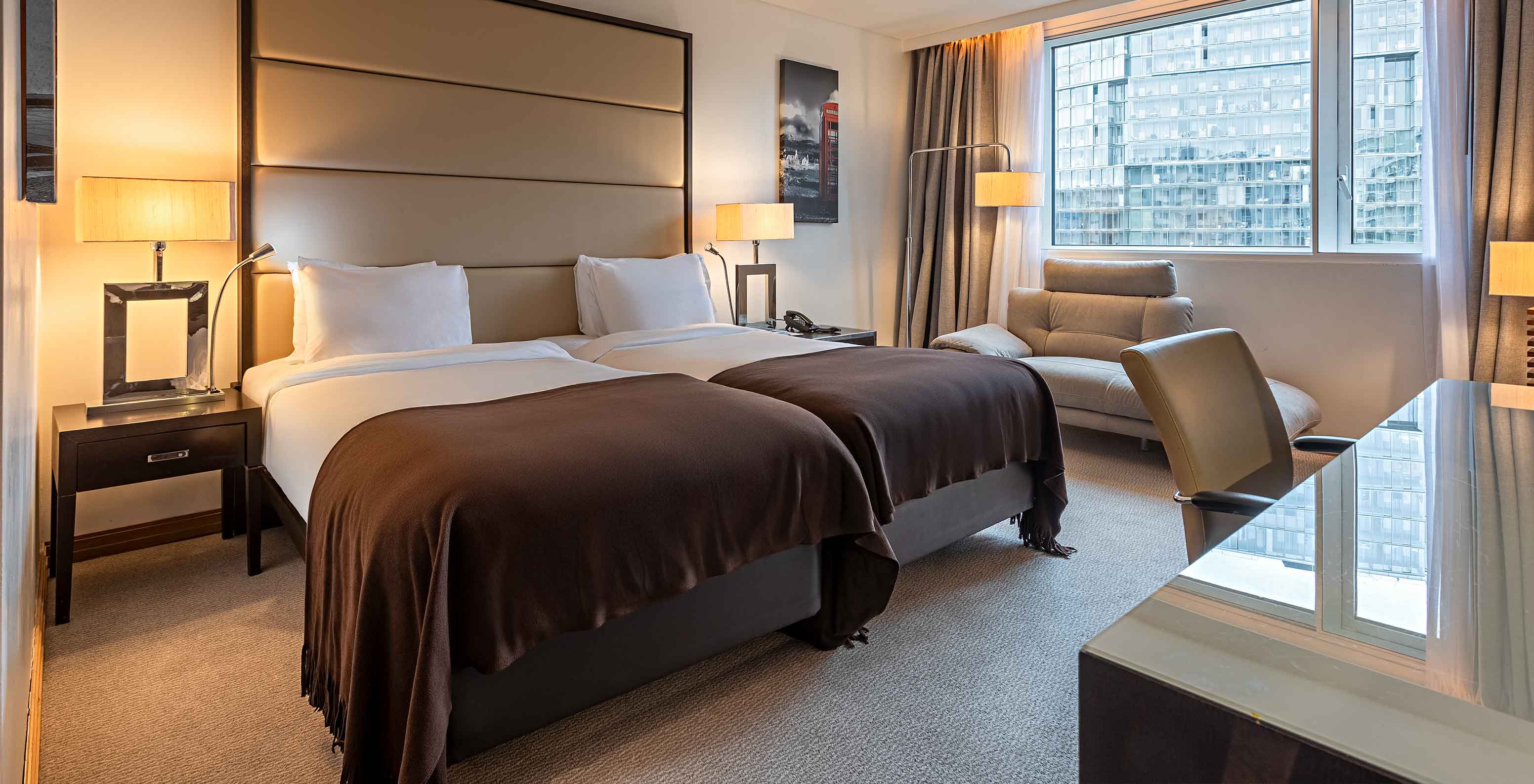 Quarto Twin Superior Vista no Pestana Chelsea Bridge, com duas camas, poltrona junto à janela e secretária
