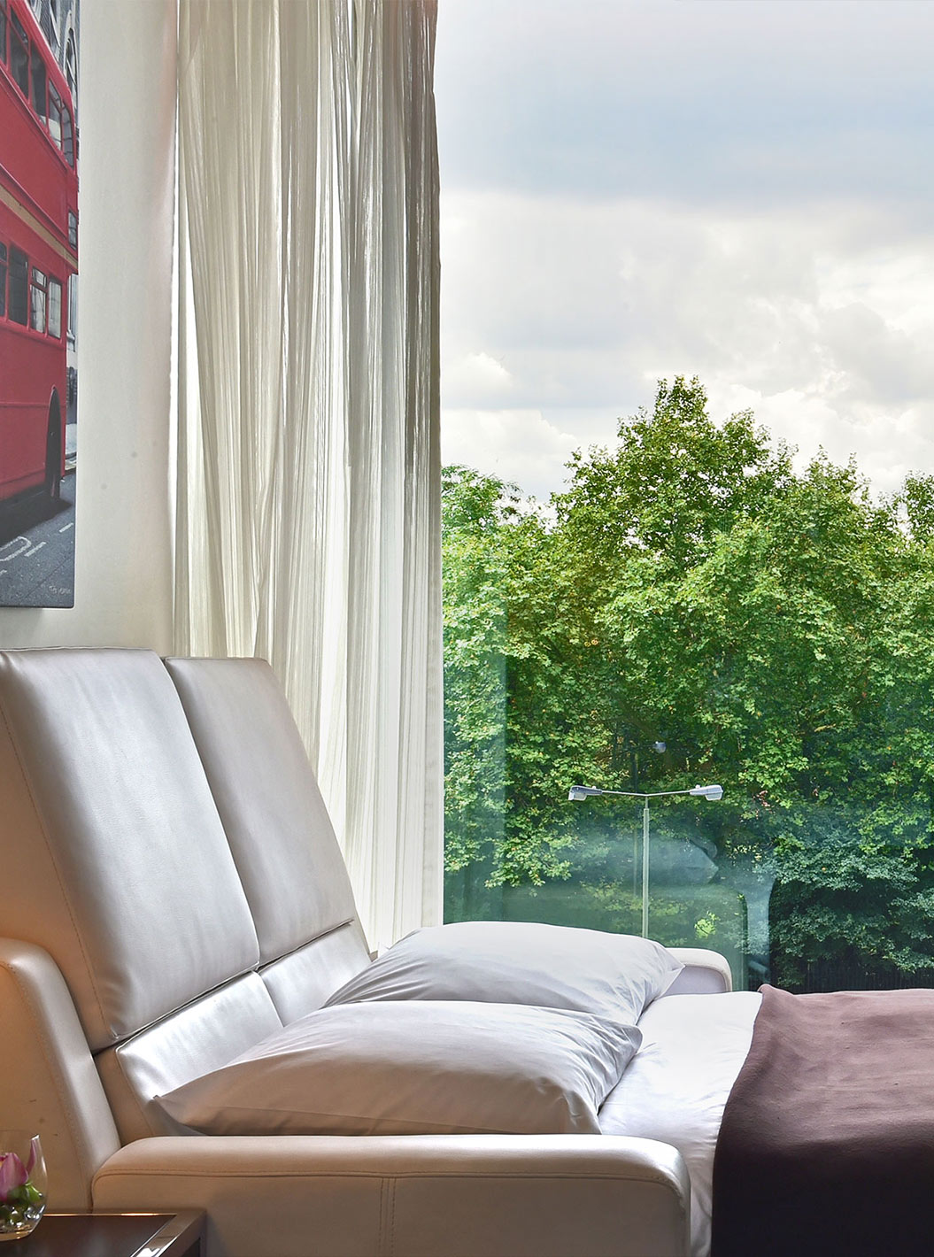 O Deluxe Family do Pestana Chelsea Bridge tem sofá cama aberto, quadros de londres e janela grande com vista e cortinas