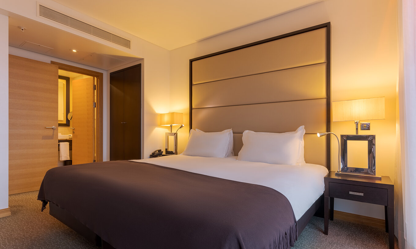 A Suite Executiva com 1 Quarto e Varanda do Pestana Chelsea Bridge tem cama de casal e duas mesas de cabeceira com candeeiro