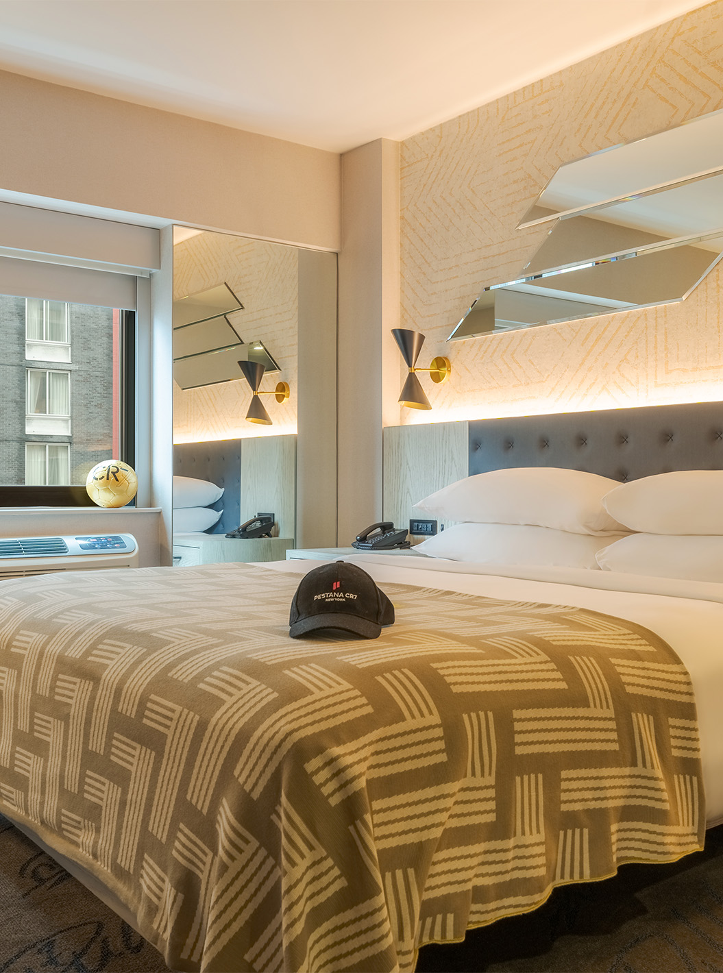 Quarto King Deluxe ADA no Pestana CR7 Times Square com cama ampla, iluminação suave e janela urbana com vista para edifícios