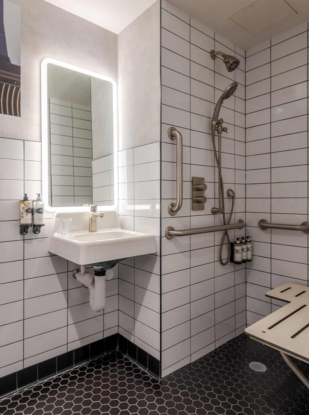 O Comfort ADA do Pestana CR7 Times Square tem uma casa de banho adaptada com duche, lavatório, e espelho