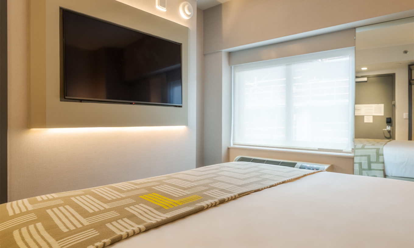 O Comfort Room do Pestana CR7 Times Square tem uma cama de casal com uma colcha com o número sete, uma televisão e uma janela