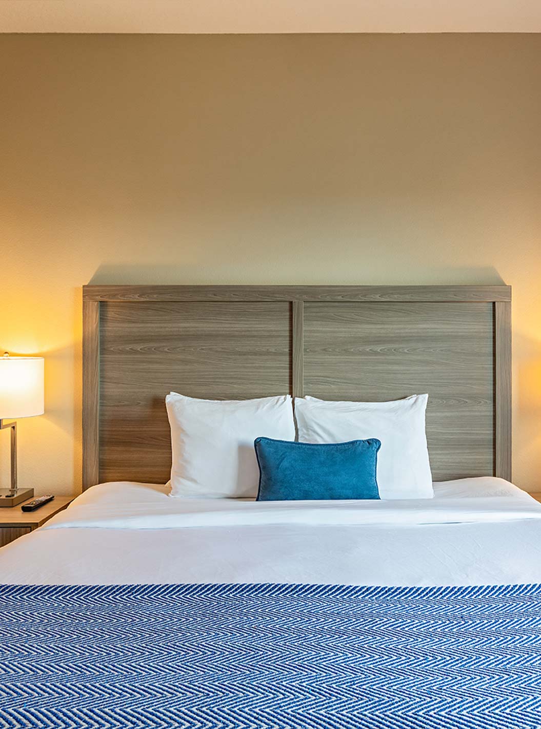 Suite King do Pestana Orlando Suites Lake Buena Vista com cama grande, almofada azul e candeeiros acesos