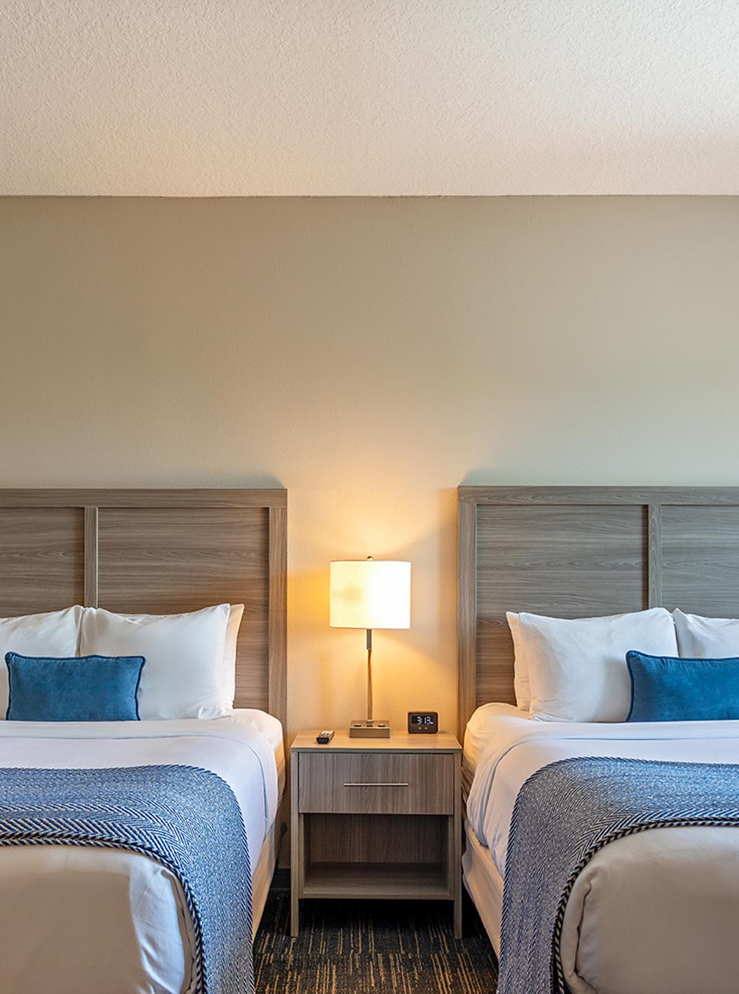 Suite Dupla Queen Superior do Pestana Orlando Suites Lake Buena Vista com duas camas, almofadas azuis e luz suave
