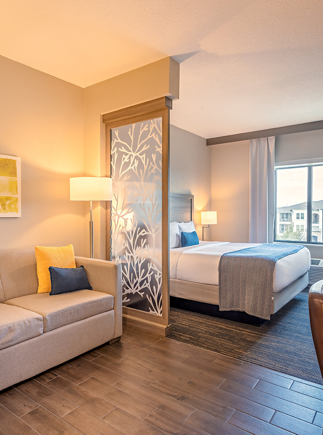 Suite King do Pestana Orlando Suites Lake Buena Vista com sofá, cama grande, secretária e janela com cortinas