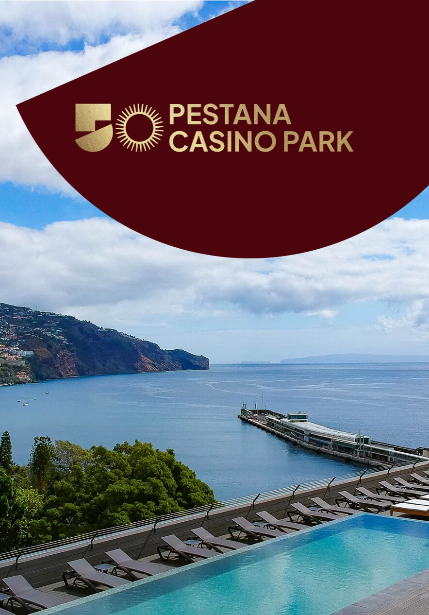 Piscina infinita com espreguiçadeiras voltada para a baía do Funchal sob céu nublado e logótipo Pestana Casino Park