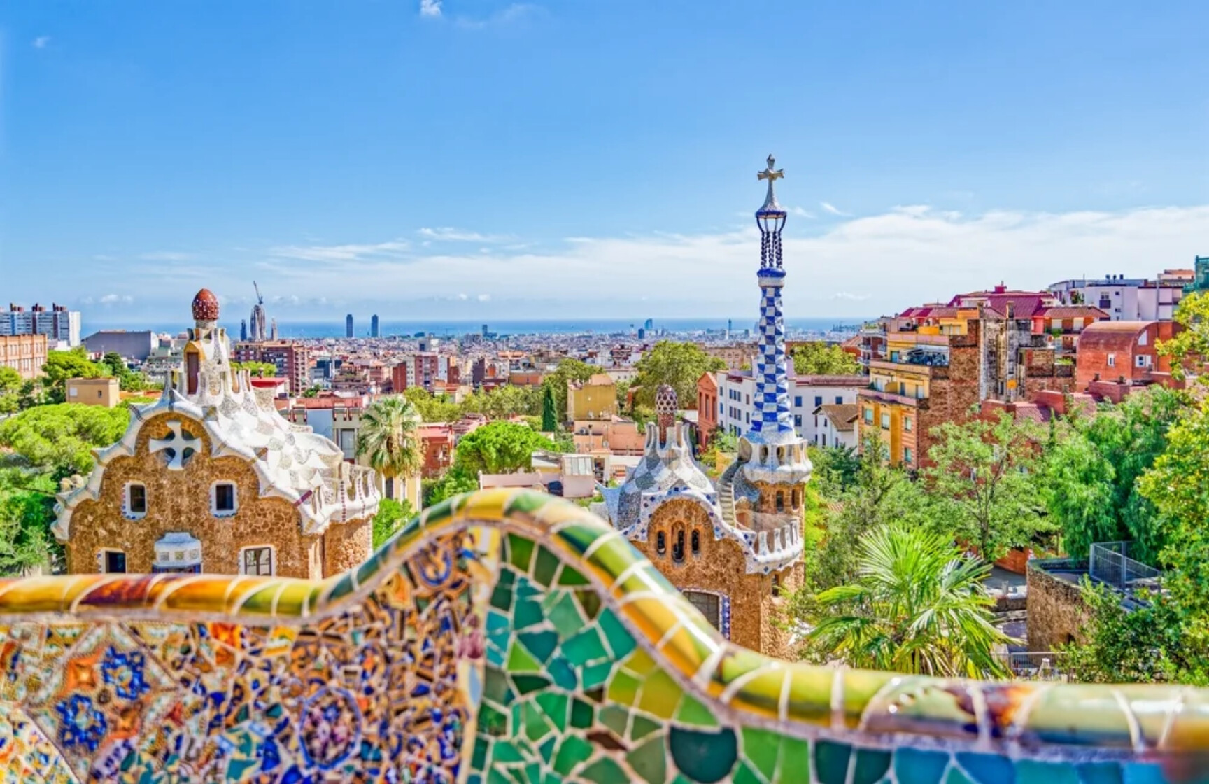 Vista panorâmica do Parque Güell em Barcelona com mosaicos coloridos, torres ornamentadas e céu limpo