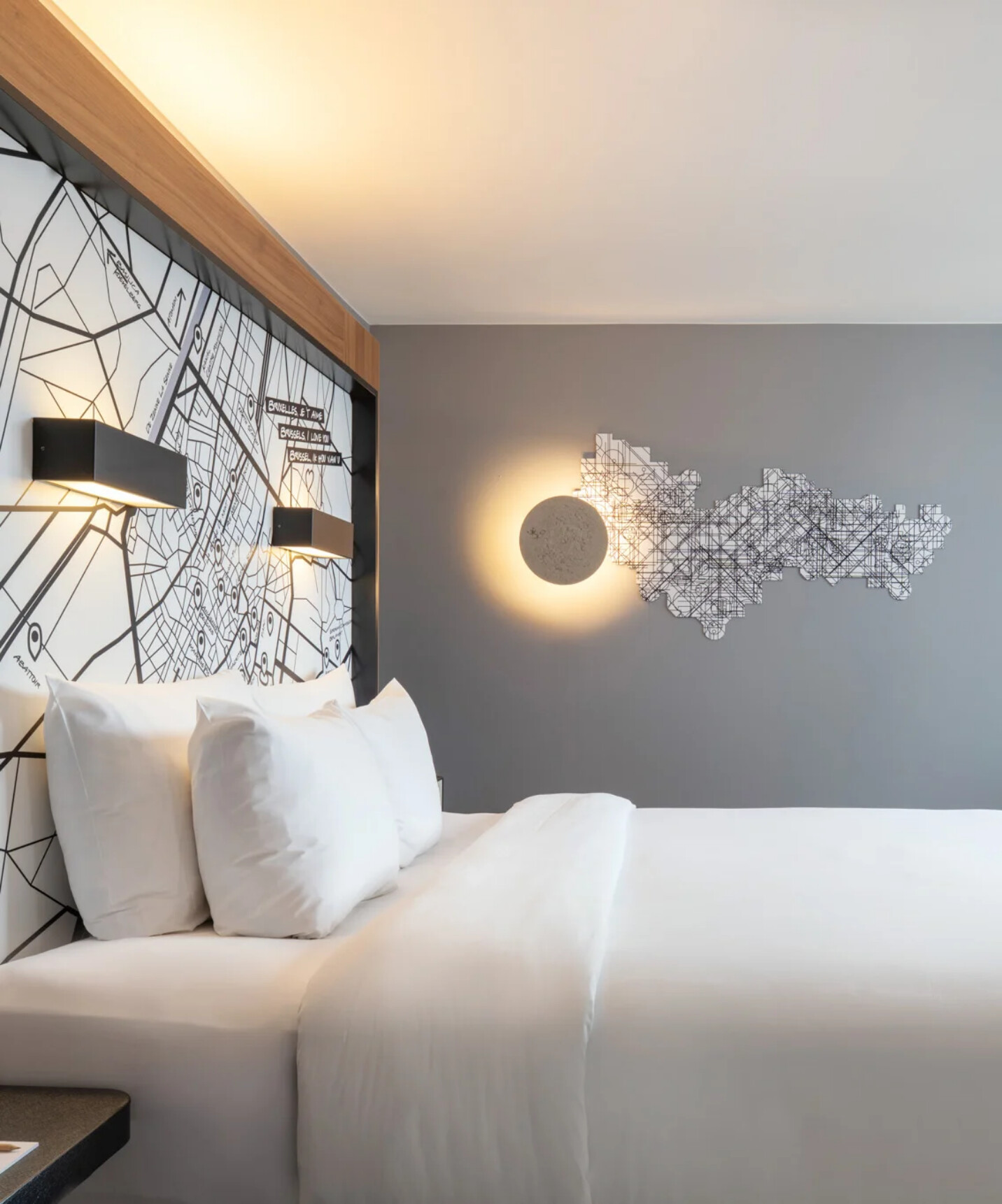 Brussels Schuman hotel com quarto moderno de cama branca, parede cinzenta e mapa urbano na parede
