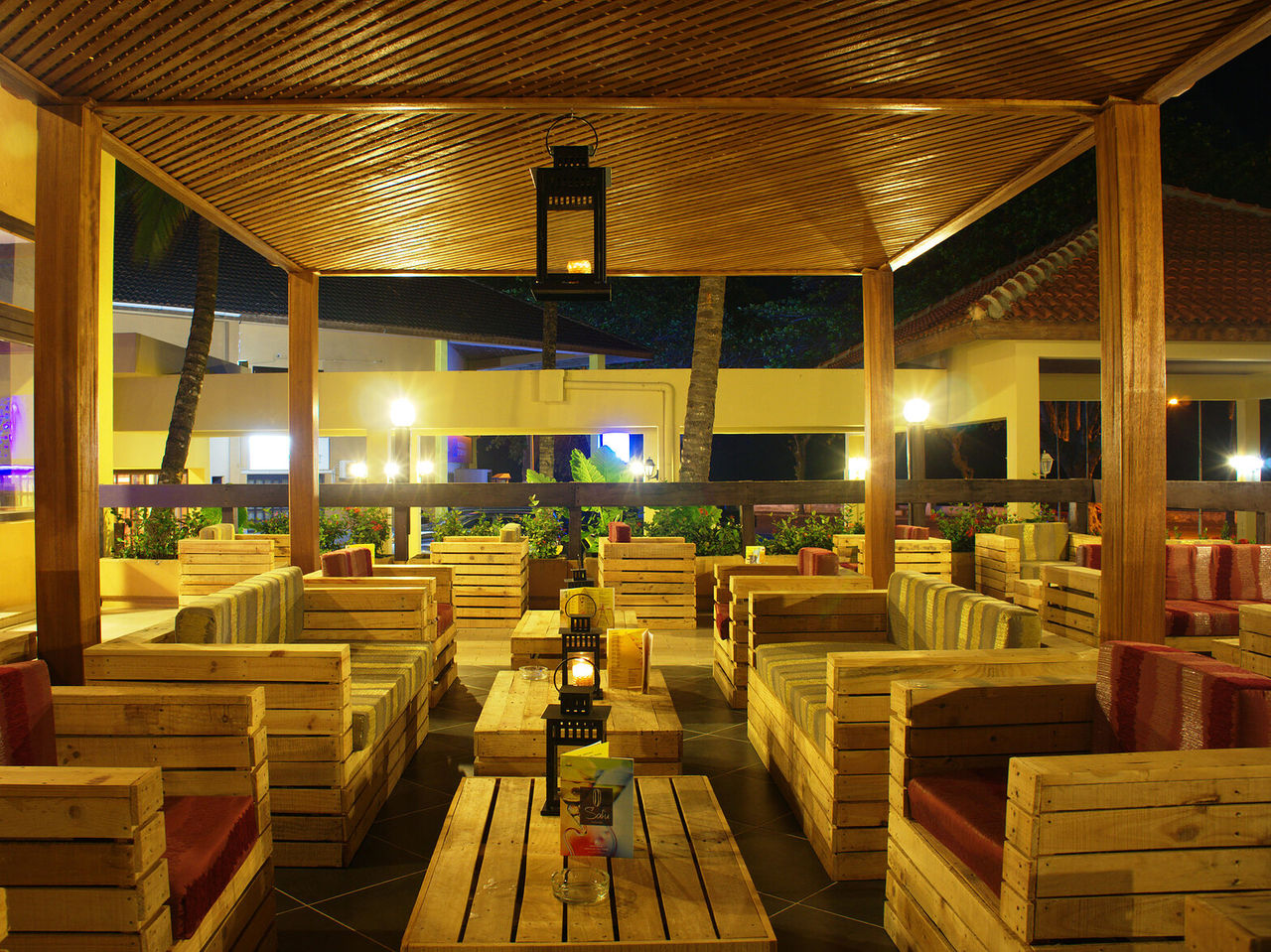 Die Bar Safu im 4-Sterne-Hotel in São Tomé hat mehrere Tische mit Holzsofas und bunten Kissen