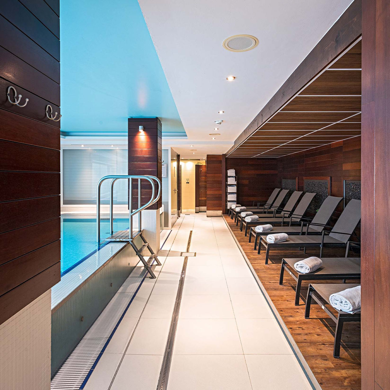 Innenpool des Pestana Berlin, mit warmem, klarem Wasser und Liegen rund um den Pool