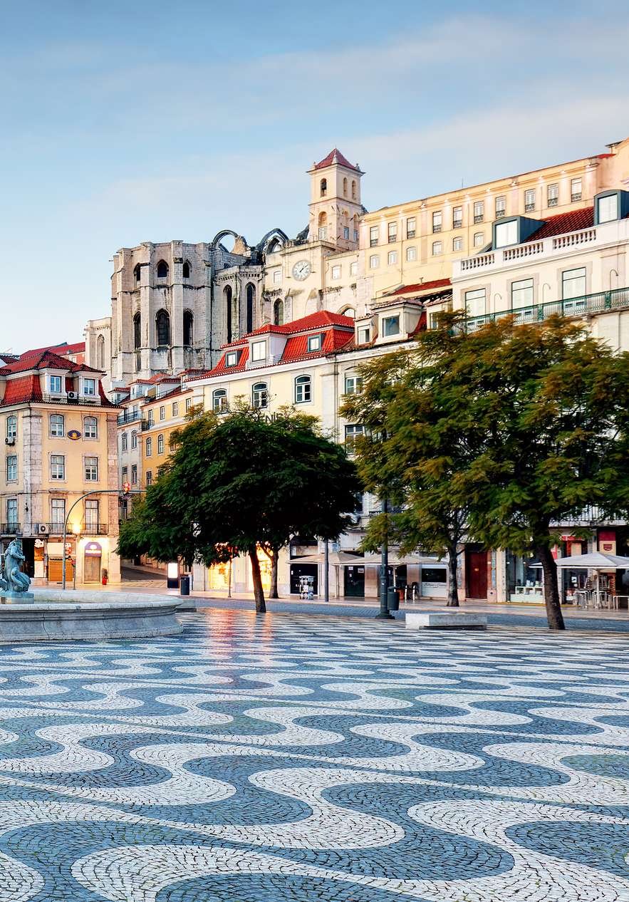 Blick auf die Praça do Rossio mit portugiesischem Pflaster, einem zentralen Brunnen mit Statuen und vielen Gebäuden