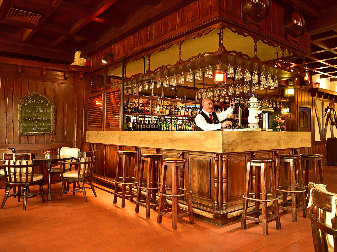 Die Bar The Pub im 5-Sterne-Hotel auf Madeira hat eine Theke, umgeben von hohen Stühlen und verschiedenen Getränken