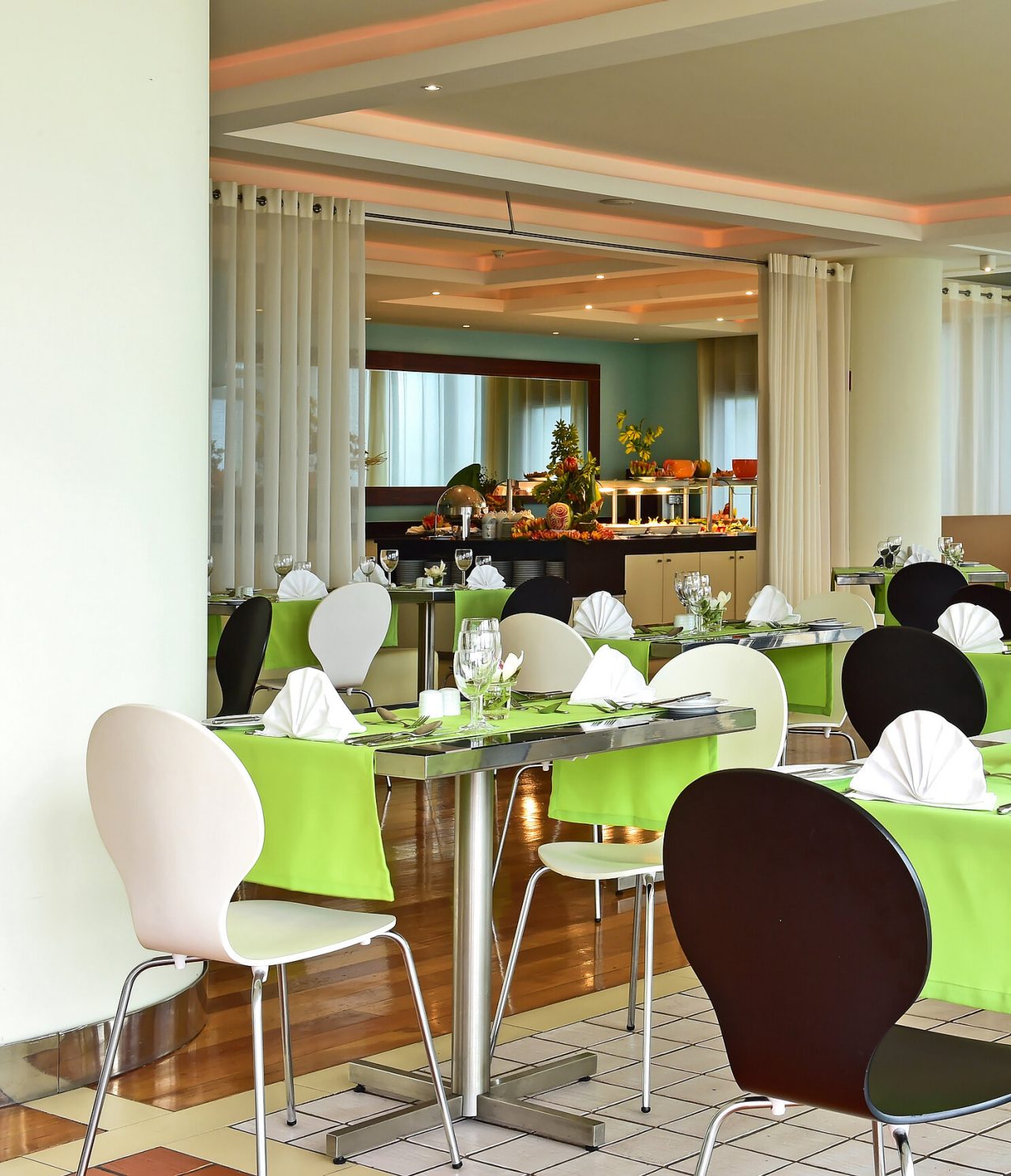 Das Restaurant Breezes im am Meer in Funchal hat mehrere Tische mit grünen Tischdecken und ein Buffet im Hintergrund