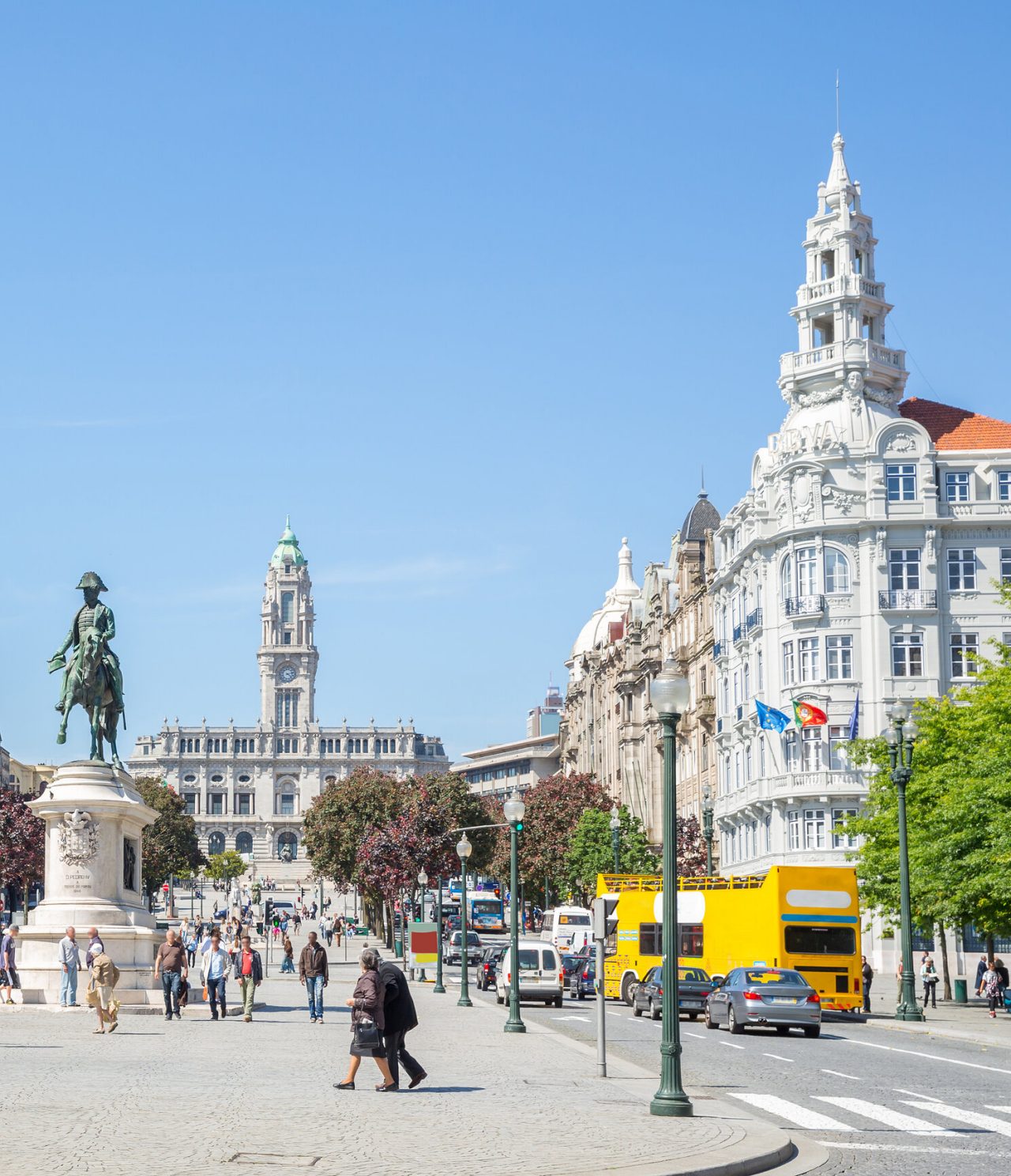 Trubel auf der Avenida dos Aliados in Porto, mit Menschen, die spazieren gehen, Autos im Verkehr und ikonischen Gebäuden