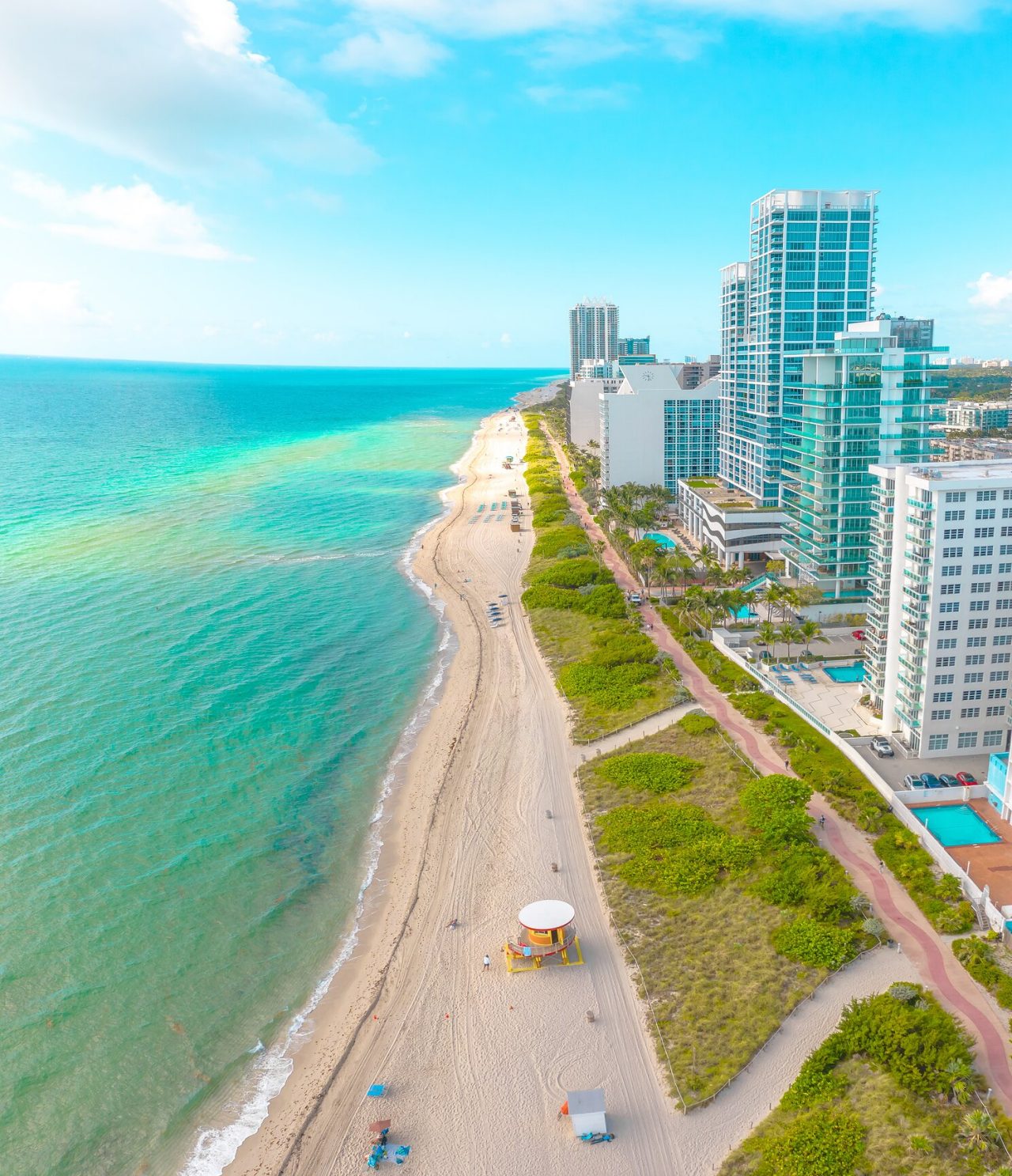 Strand von Miami Beach, Florida, mit weißem Sand, türkisfarbenem wasser und Menschen, die schwimmen und sonnenbaden