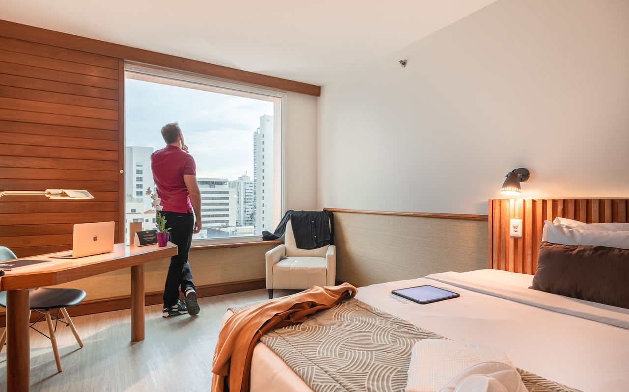 Mann genießt die Aussicht aus einem Hotelzimmerfenster im Pestana São Paulo im Stadtzentrum