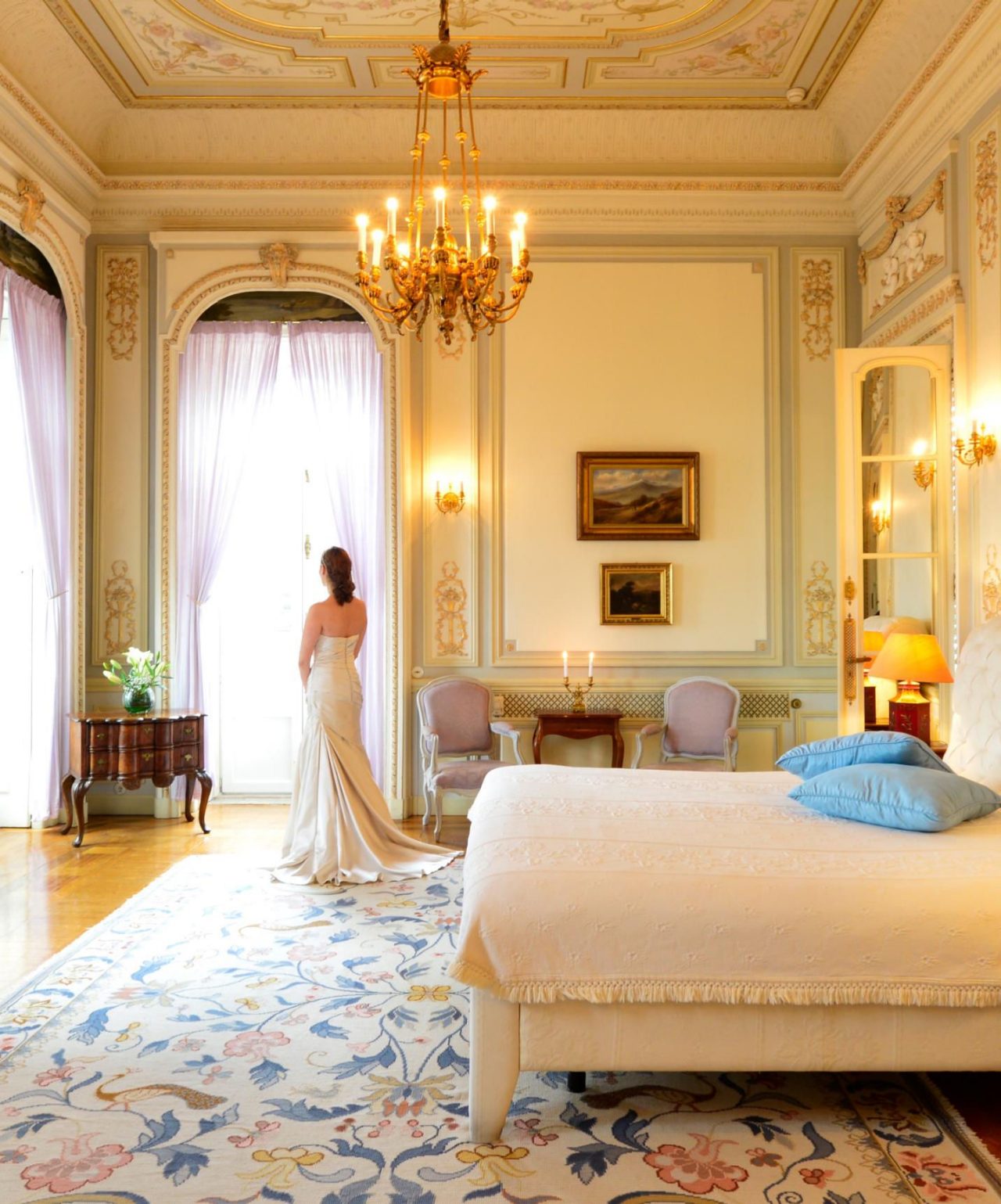 Braut bereitet sich auf ihre Hochzeit in einem eleganten Hotelzimmer vor, mit Wänden, die mit goldenen Details und einem Kristallleuchter geschmückt sind