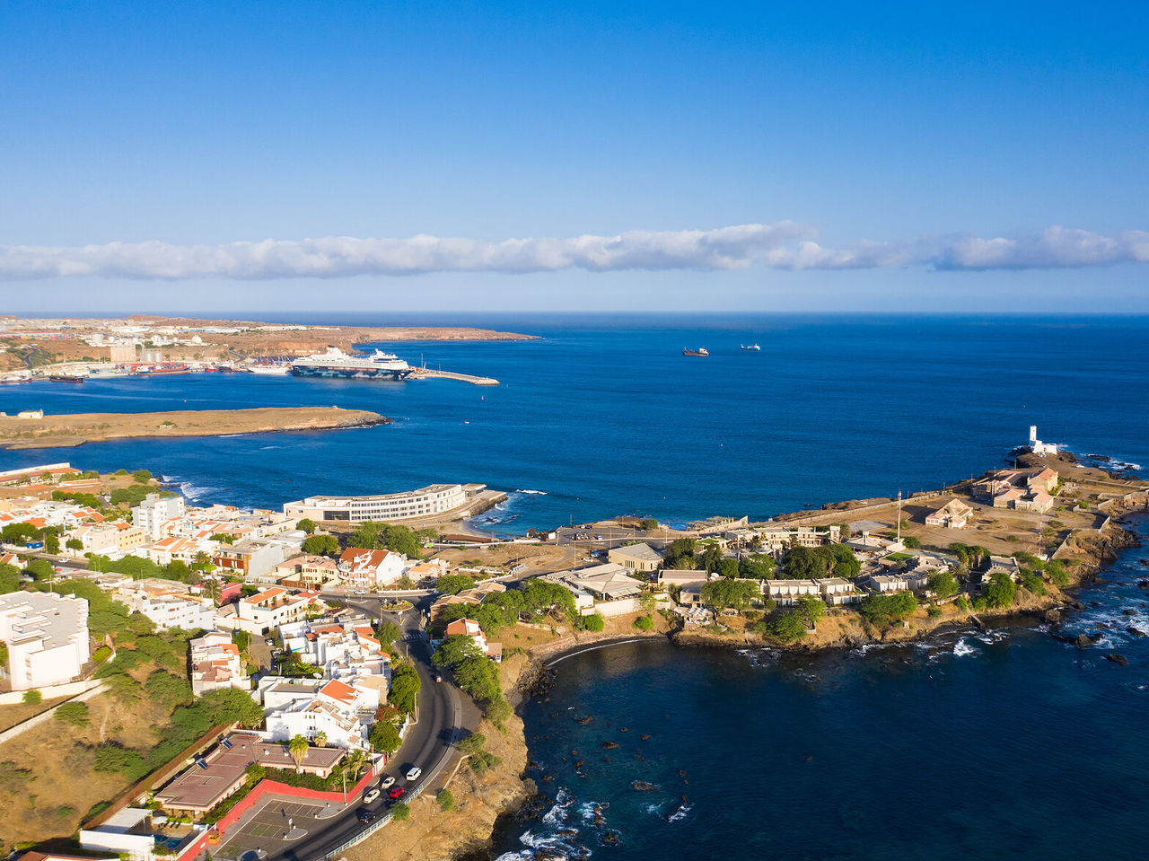 Explore Hotels in Cidade da Praia with an aerial view of the coastal harbor, blue ocean and rocky shoreline
