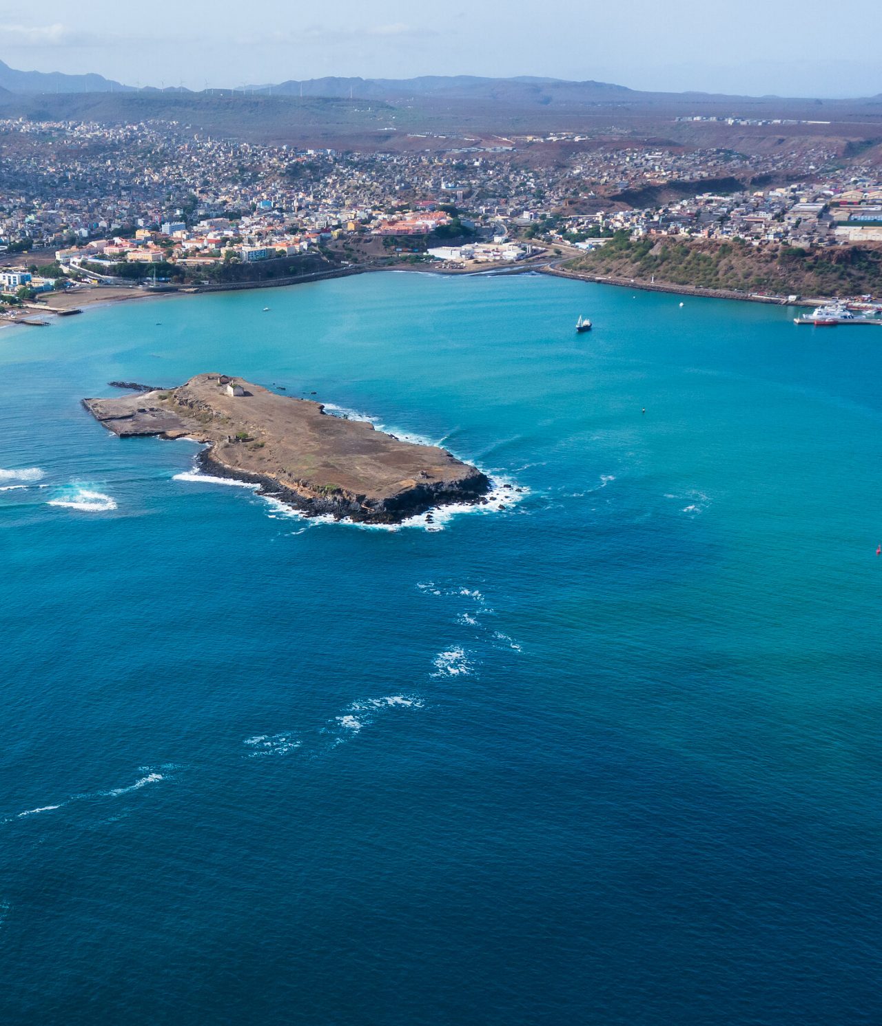 Explore Hotels in Cidade da Praia with an aerial view of the bay, rocky island and coastal cityscape