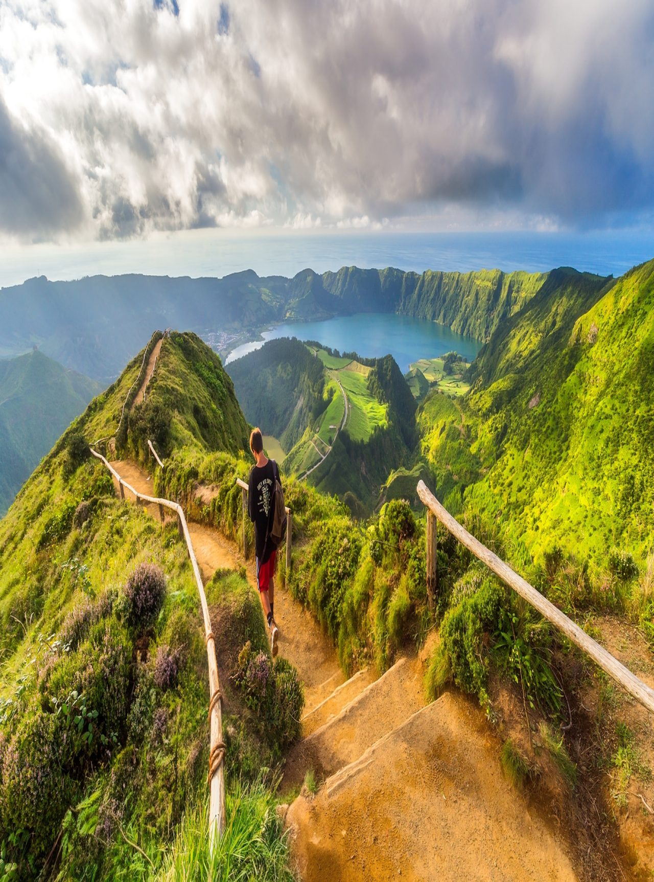 Man walks on a dirt trail with a view of Sete Cidades Lagoon, São Miguel Island, Azores