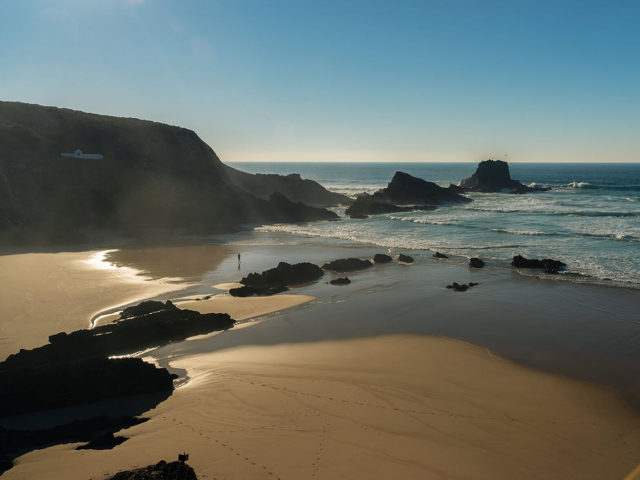 Explore Hotels in Alentejo featuring a quiet rocky beach with ocean waves and golden sand at sunset