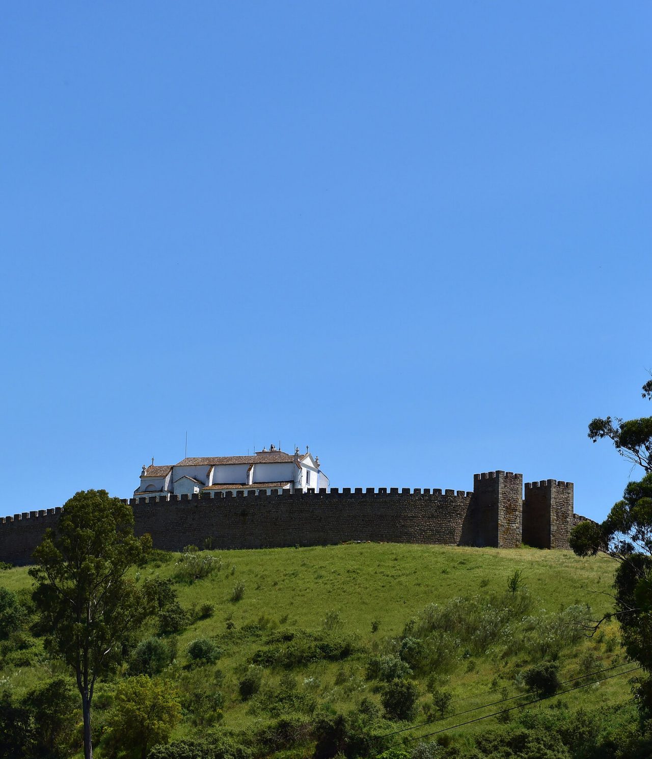 Historic castle on top of a hill in Arraiolos, Alentejo, surrounded by green landscapes and clear blue sky