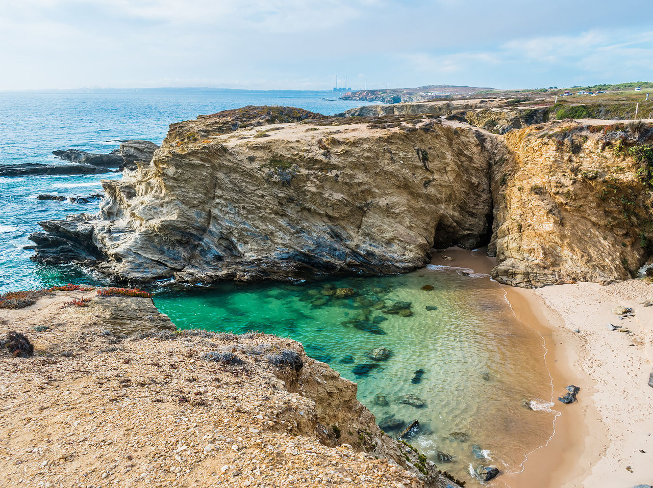 Explore Hotels in Alentejo featuring rugged coastal cliffs above a small sandy cove with clear turquoise water