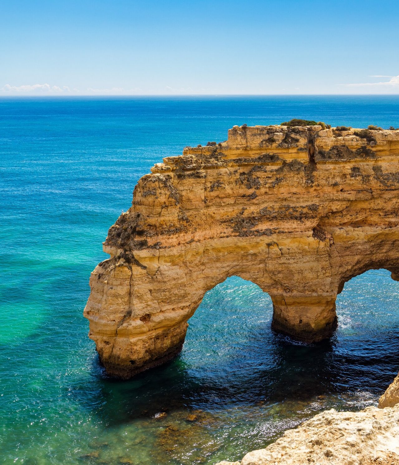 Explore Hotels in the Algarve featuring golden coastal cliffs rising above clear blue Atlantic waters