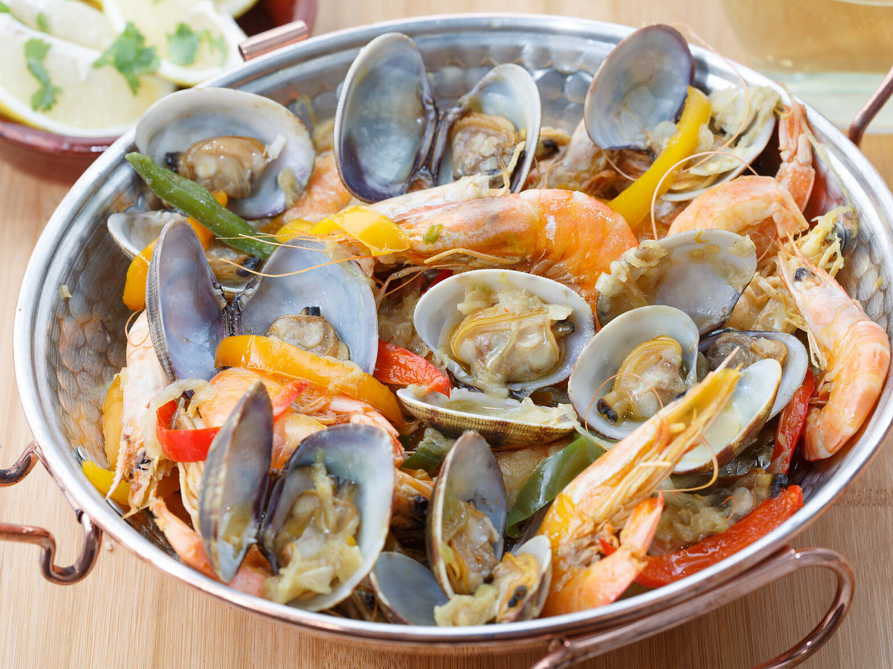 Traditional dish from the Algarve region, a seafood cataplana with clams, shrimp, and peppers, with lemon