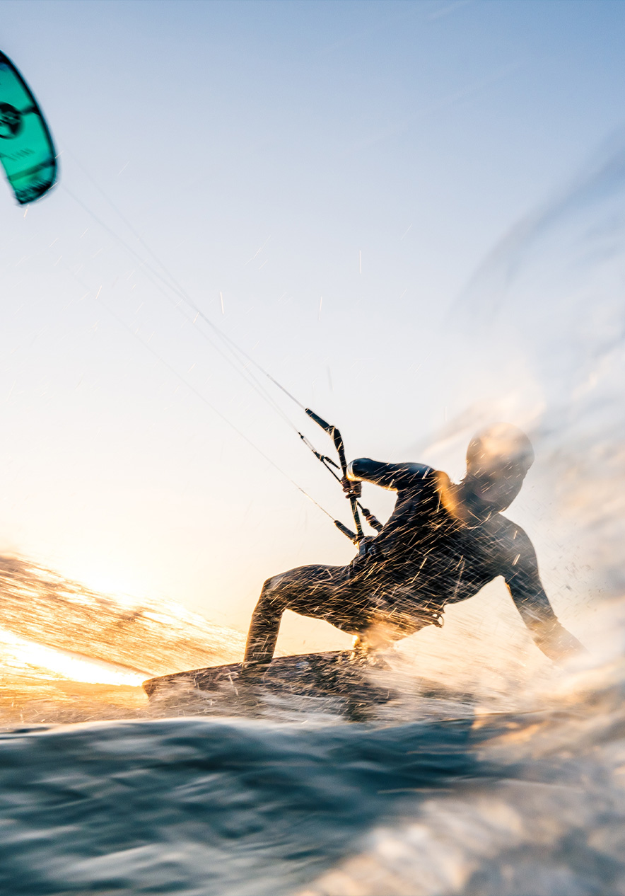 Boy kitesurfing on the blue waters of the Algarve gliding over the waves with his colorful kite against the clear sky
