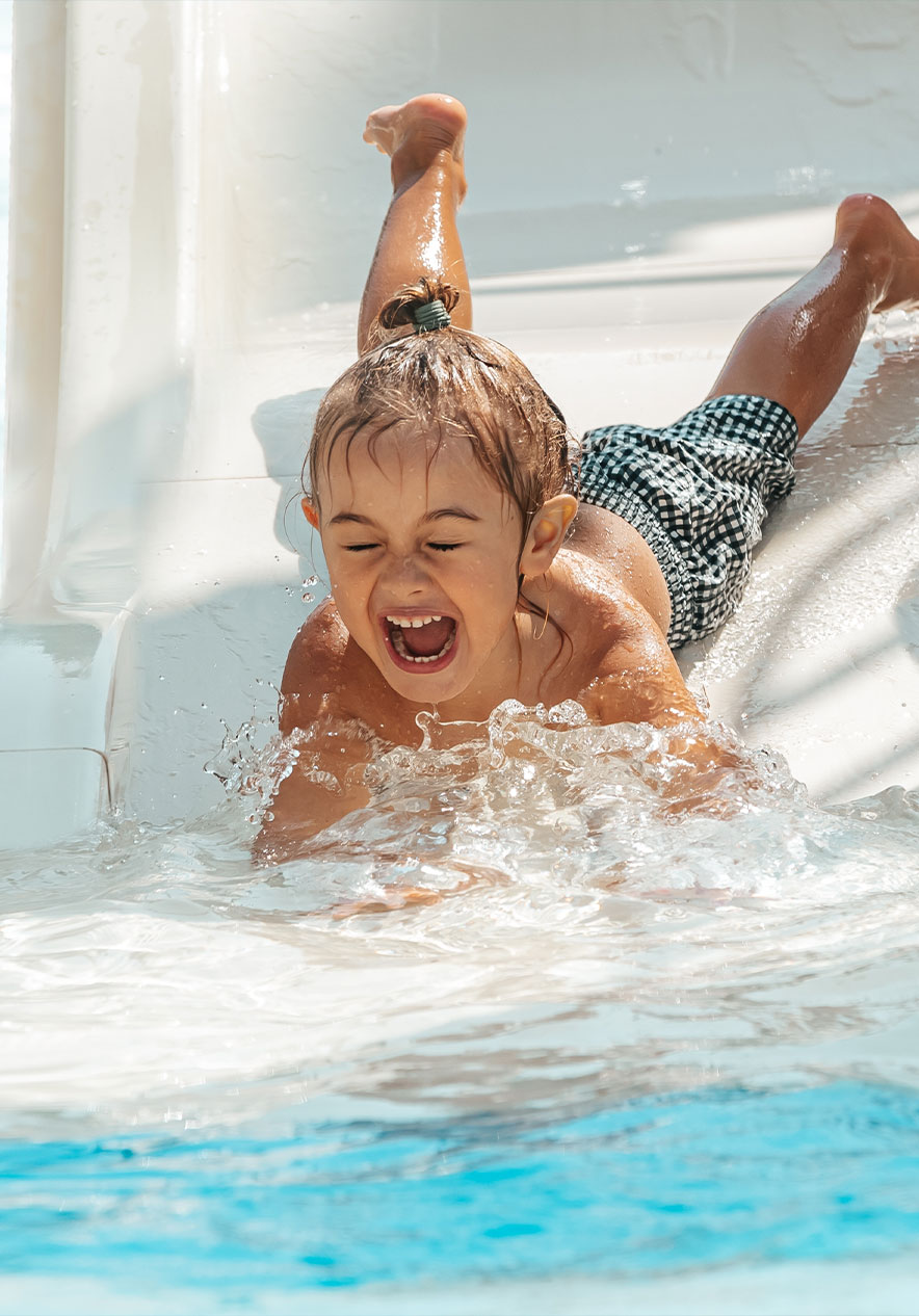 Child smiling while sliding down a water slide at Slide and Splash in the Algarve