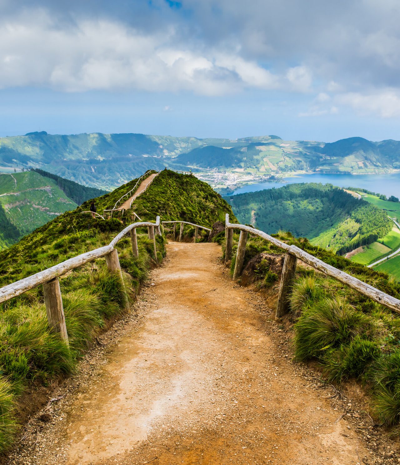 Explore Hotels in the Azores overlooking a mountain trail with wooden fences above green volcanic lakes