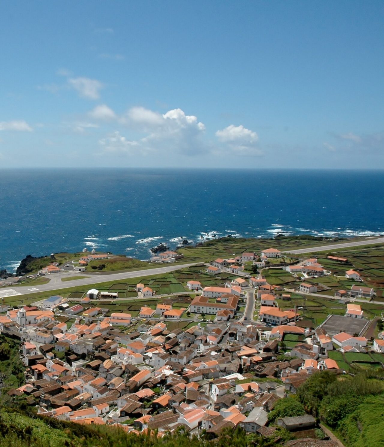 Explore Hotels in the Azores with an aerial view of a coastal village, green fields and blue Atlantic waters
