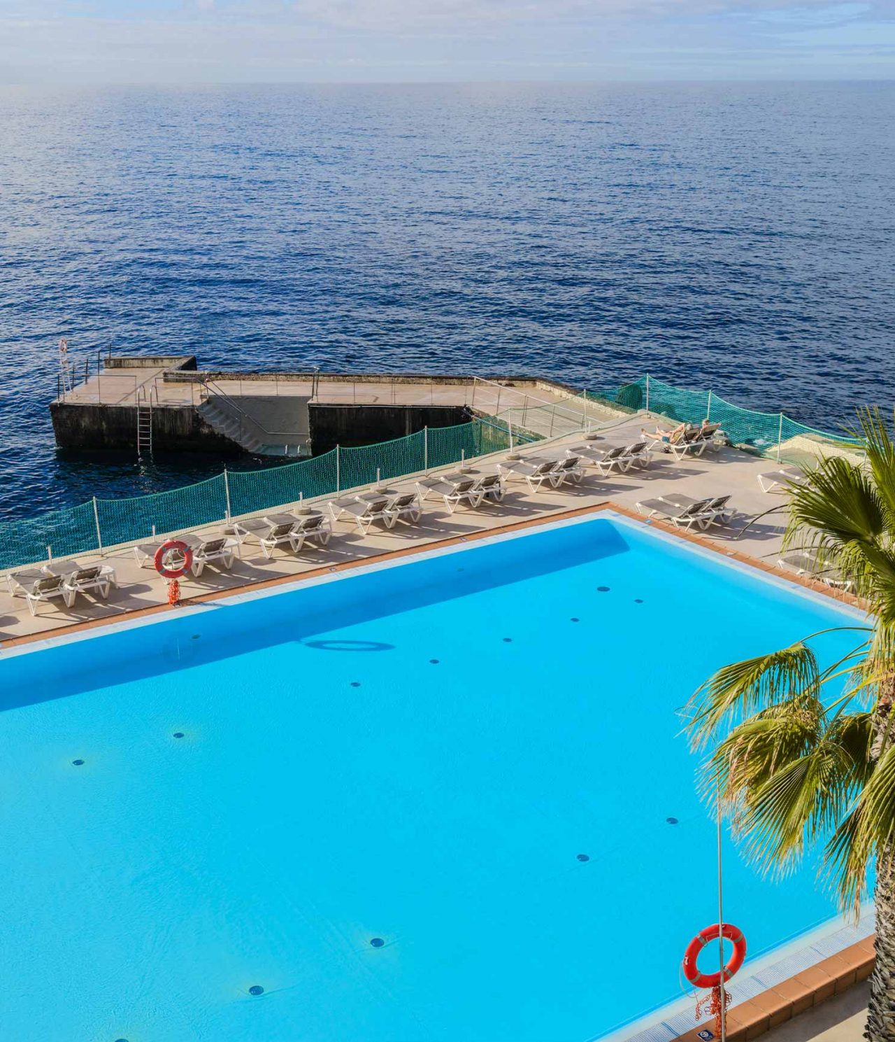 Bar at Pestana Carlton Madeira, 5-Star Hotel in Madeira, overlooking an oceanfront pool with loungers